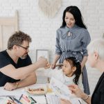 Child with foster parents and a social worker discussing adoption at home.