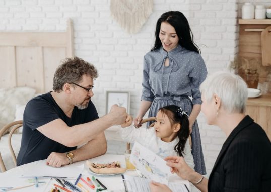 Child with foster parents and a social worker discussing adoption at home.